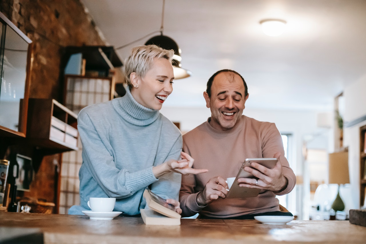 man and woman laughing at something on iPad 