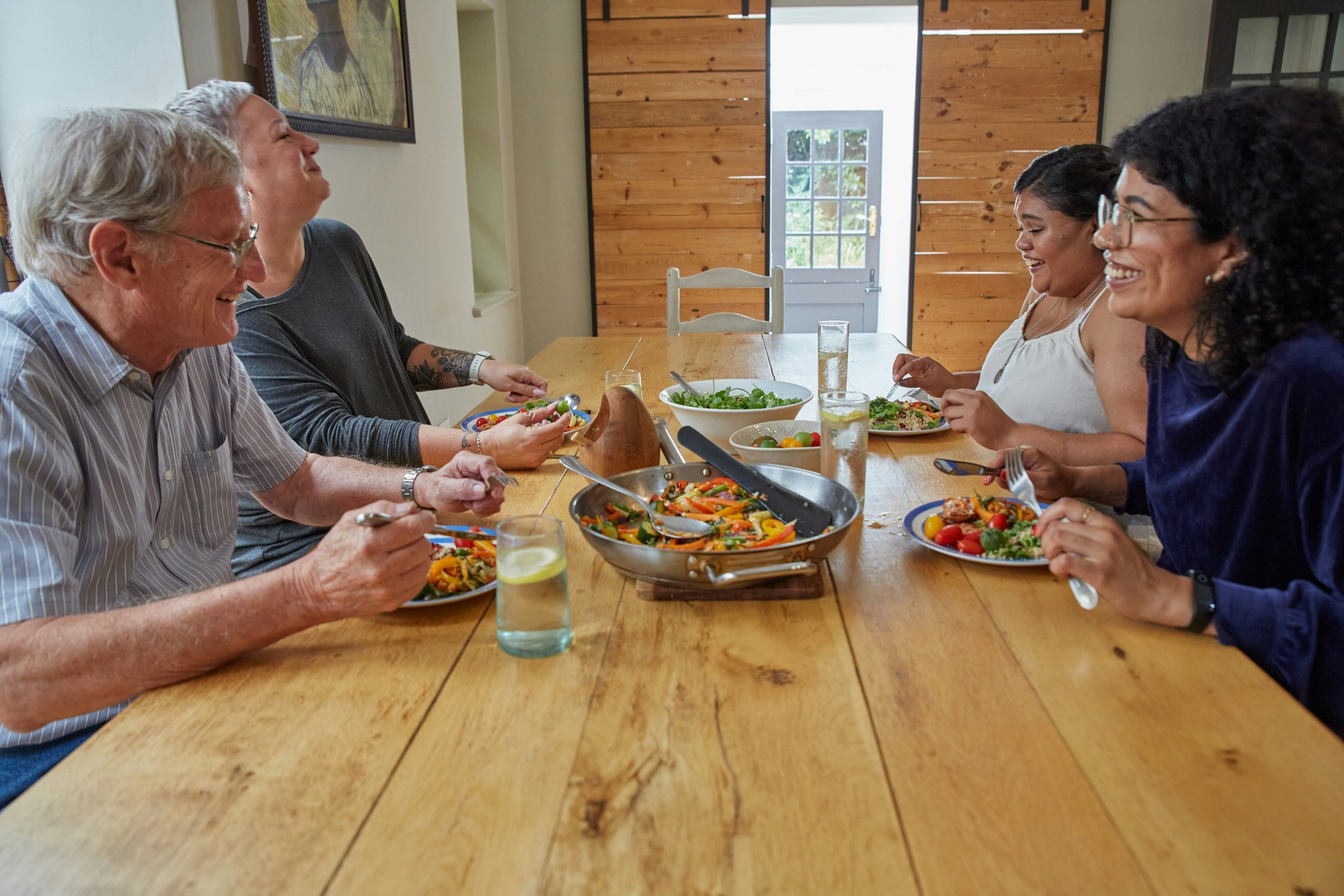 Four people sitting around a table, talking, laughing, and eating.