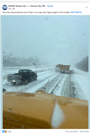 Picture from the dashboard of a snow plow on a snowy day and the traffic. 