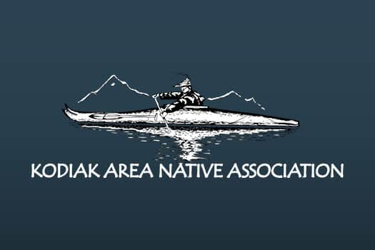 Kodiak Area Native Association's company logo consists of a gray/blue background with a person in a one-person kayak-like boat paddling in the water. Behind them are mountains. Underneath this image is the capitalized, white text "KODIAK AREA NATIVE ASSOCIATION."