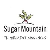 Sugar Mountain's company logo consists of a white background with a carrot in the ground, exposing its green leaves. Underneath the ground are the words: Sugar Mountain. Underneath that are the capitalized words: TRUSTED DELICIOUSNESS