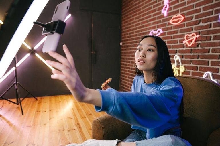 A woman using her phone while attached on a ring light