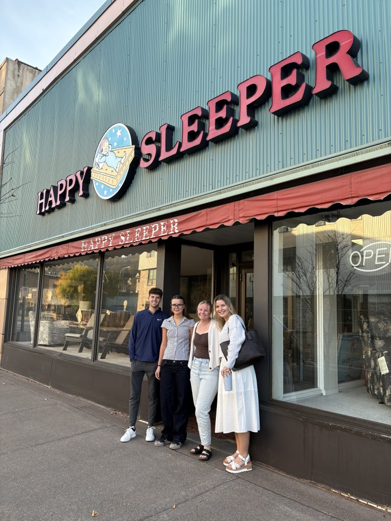 Marketing, business, and management students standing in front of the Happy Sleeper mattress store.